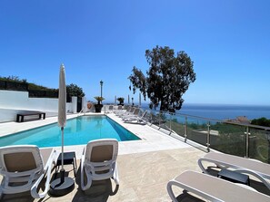 Zona de piscina con sillones, una piscina y vistas al océano.