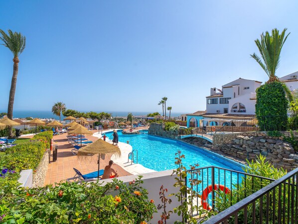 Ein Pool im Resort mit Blick auf das Meer, umgeben von Palmen und Liegestühlen.