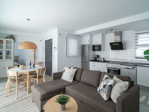 Ein modernes Wohnzimmer mit Sofa, Couchtisch und Essbereich.