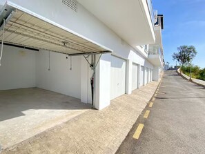 A building with a covered parking area, a clear sky, and a paved road with yellow lines. - Penthouse Balcon del Mar 121 by Casasol by Interhome (Nerja)