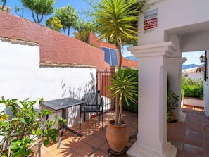 A patio area with a table and chairs, a potted plant, and a sign indicating a security alarm system. - Villa Prime Seaview by Casasol by Interhome (Nerja)