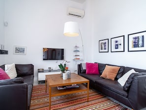 A modern living room with a black leather sofa, a wooden coffee table, a flat-screen TV, and a patterned rug. - Villa Prime Seaview by Casasol by Interhome (Nerja)