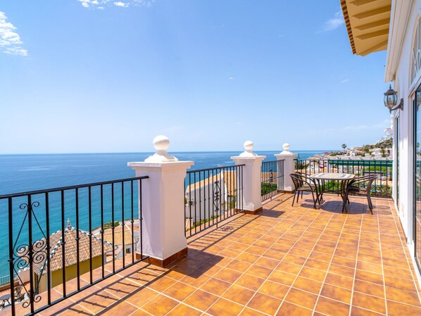 A terrace with a view of the sea, featuring a tiled floor, a table with chairs, and a railing. - Villa Prime Seaview by Casasol by Interhome (Nerja)
