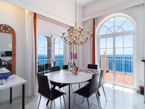 A spacious dining area with a round table, black chairs, and a chandelier. - Villa Prime Seaview by Casasol by Interhome (Nerja)