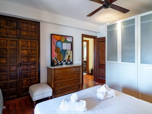 Een hotelkamer met een bed, een dressoir, een plafondventilator en een schilderij.