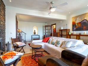 A spacious living room with a large sofa, a ceiling fan, and a fireplace. - Capistrano Village Casa Garden by Interhome (Nerja)