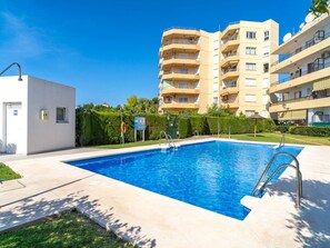 A swimming pool with a clear blue water, surrounded by a paved area, and a multi-story building with balconies in the background. - Tahiti 2 7 by Casasol by Interhome (Nerja)