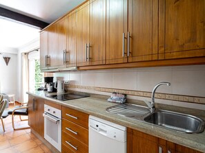 A kitchen with wooden cabinets, a stainless steel sink, a dishwasher, and a coffee maker. - Tahiti 2 7 by Casasol by Interhome (Nerja)