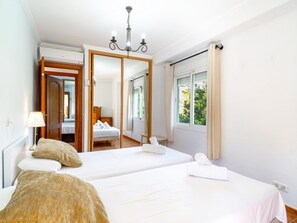 A hotel room with two beds, a large mirror, a chandelier, and a window with curtains. - Tahiti 2 7 by Casasol by Interhome (Nerja)
