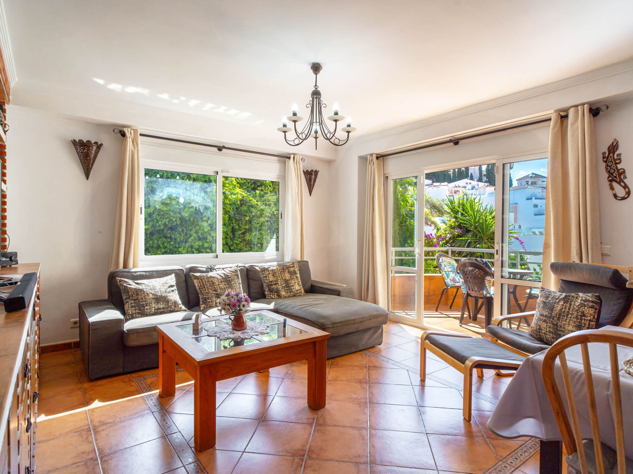 A spacious living room with a sofa set, a coffee table, and a balcony with outdoor furniture.