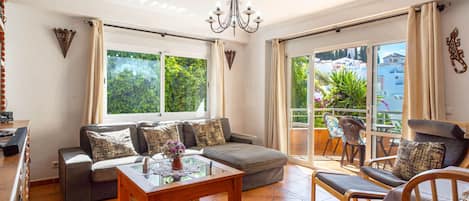 A spacious living room with a sofa set, a coffee table, and a balcony with outdoor furniture.