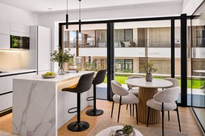 Une cuisine moderne dotée d’un plan de travail en marbre, d’un four encastré et d’un coin repas avec une table ronde et des chaises.