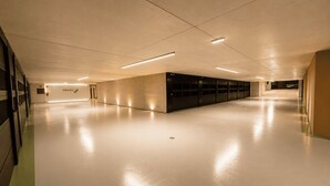 Un'ampia area interna ben illuminata, con un lungo corridoio e una fila di armadietti chiusi su un lato.