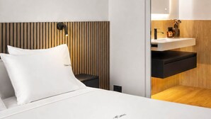 Una camera d'albergo moderna con un letto, un comodino, uno specchio e una parete rivestita in legno.