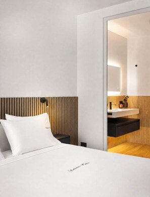 A modern hotel room with a bed, a bedside table, a mirror, and a wooden panel wall. - NEW: Casa Jasmina - Residence Corte Carden 2 (Bardolino)