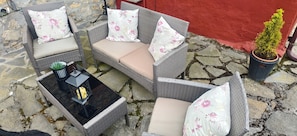 A wicker outdoor seating area with cushions and a table, set on a stone patio.