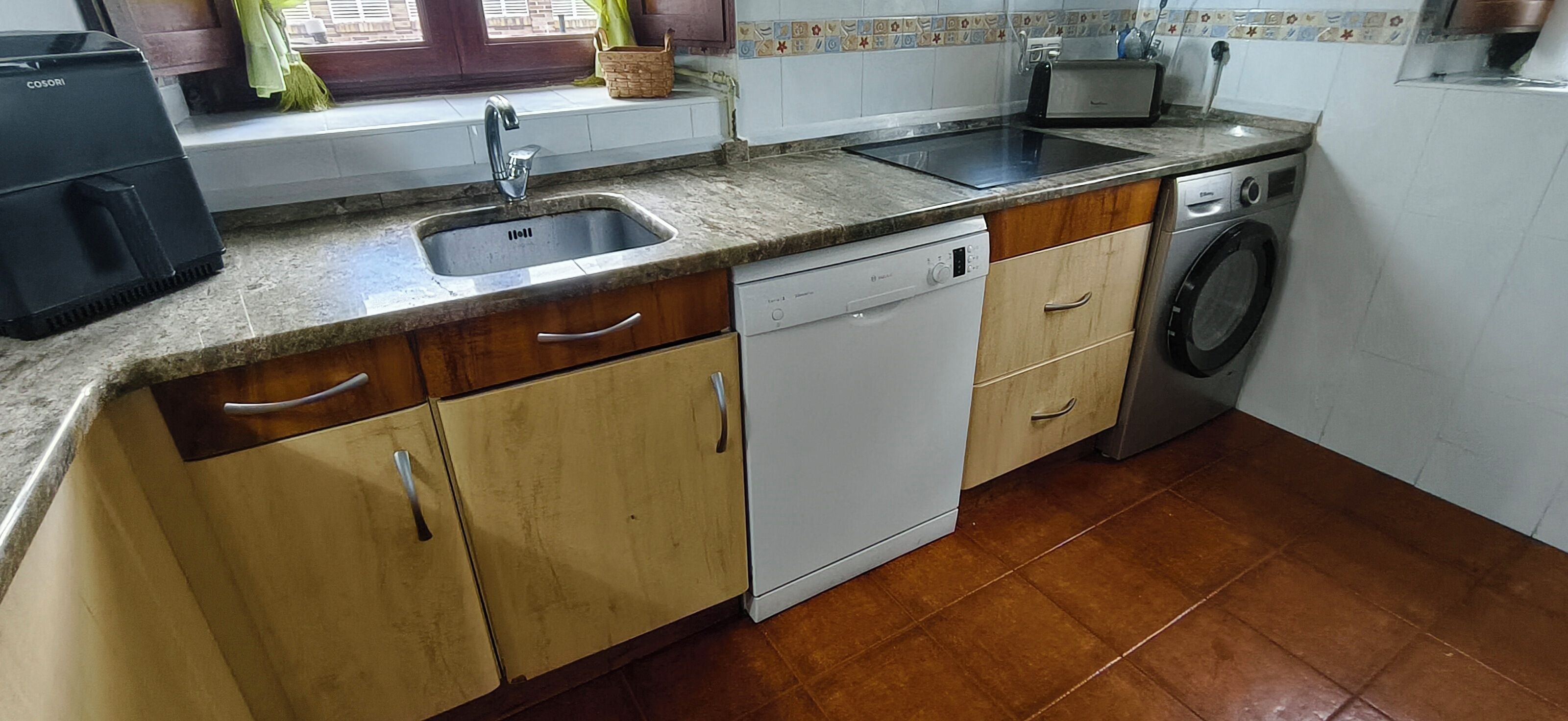 Een keuken met een spoelbak, vaatwasser en wasmachine.