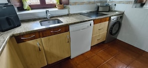 A kitchen with a sink, dishwasher, and washing machine.
