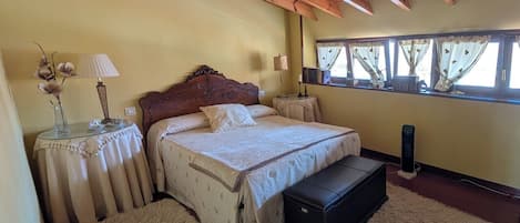 Un dormitorio con techo de madera, una cama con cabecera, mesitas de noche, una ventana con cortinas y una lámpara de noche.