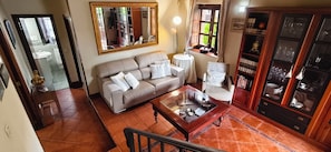 A living room with a sofa, a coffee table, a bookshelf, and a mirror.