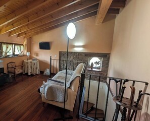 Une chambre à coucher avec un lit à baldaquin, une cheminée en pierre, un téléviseur fixé au mur et une fenêtre avec des rideaux.