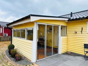 A yellow house with a glass door leading to a patio area.