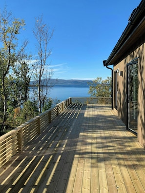 A wooden deck with a view of a lake and distant hills.