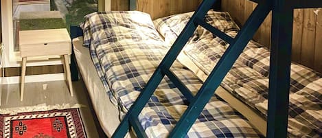 Uma cama beliche com cabeceira, mesa de cabeceira, espelho e janela com persianas.