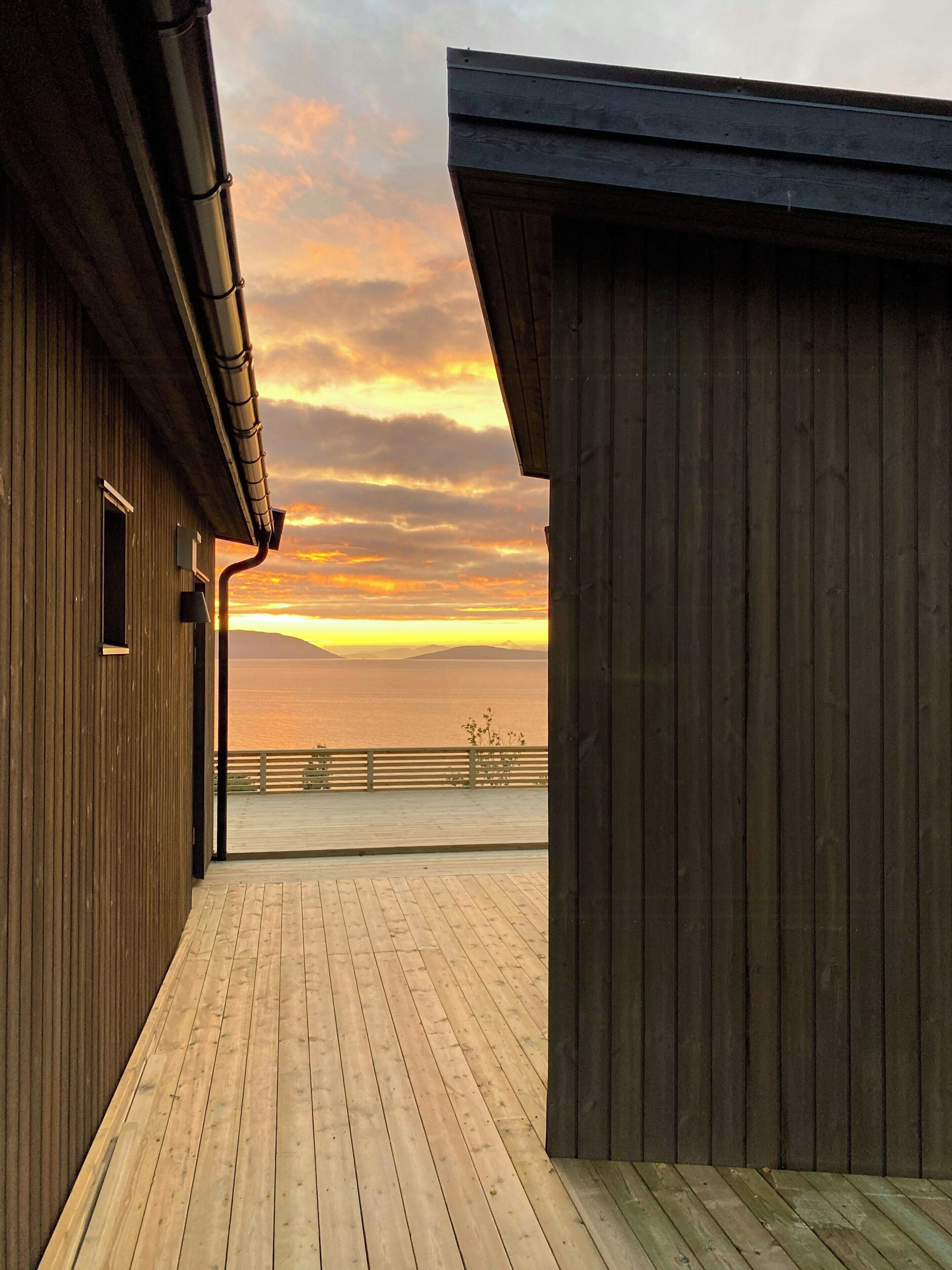 A wooden deck with a view of the sunset over the water.