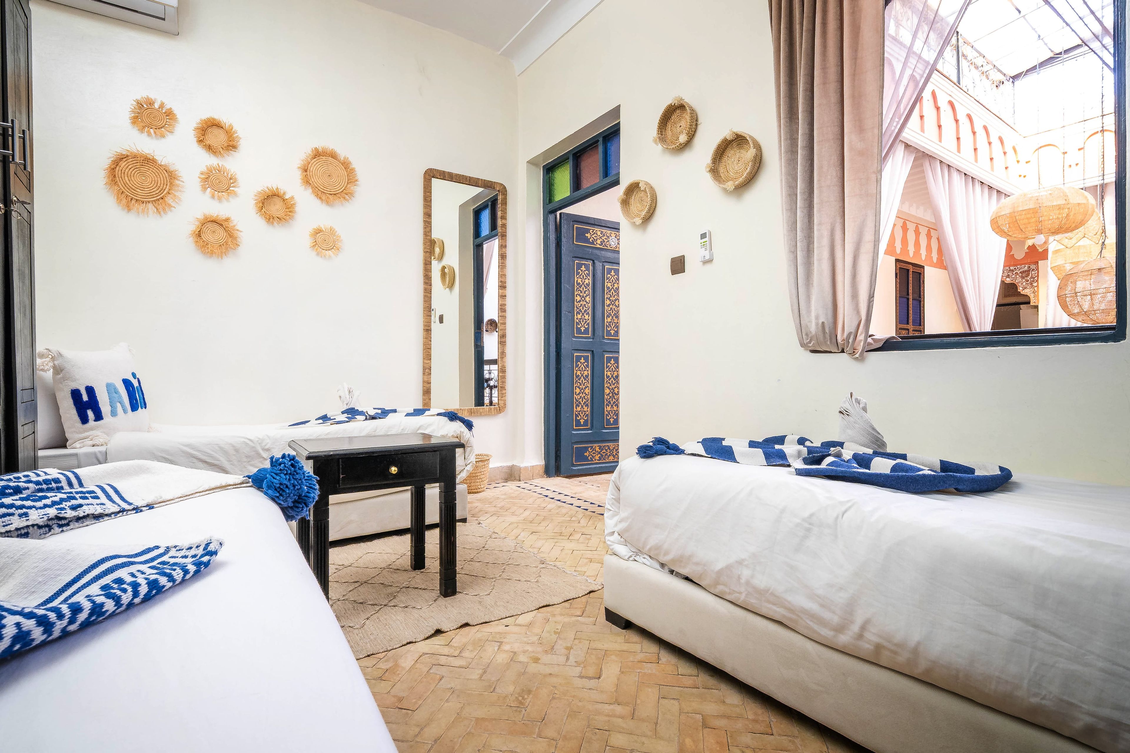 Habitación de hotel con dos camas, una mesita, un espejo y adornos en la pared.