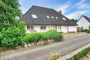 Et etplanshus med skråt tag, garage og en belagt indkørsel.