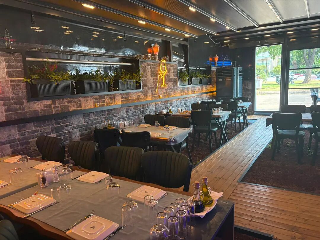 A restaurant with a brick wall, wooden tables, and chairs.