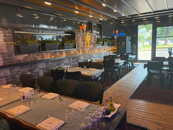 A restaurant with a brick wall, wooden tables, and chairs. - Blueberry Inn Hotel (Antalya)