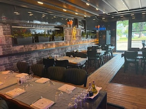Un restaurante con pared de ladrillo, mesas y sillas de madera.
