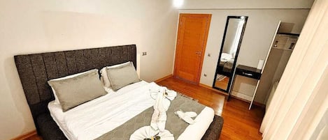 Une chambre à coucher avec un lit, un plancher en bois, une armoire et un miroir.