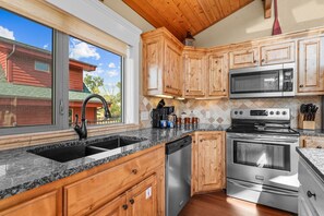 A kitchen with wooden cabinets, a stainless steel dishwasher, a double oven, and a microwave.