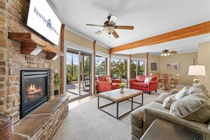 A spacious living room with a fireplace, red sofas, a coffee table, and a view of the outdoors. - Walk to Table Rock Lake from your Log Cabin-Free Daily Attraction Tickets (Branson)