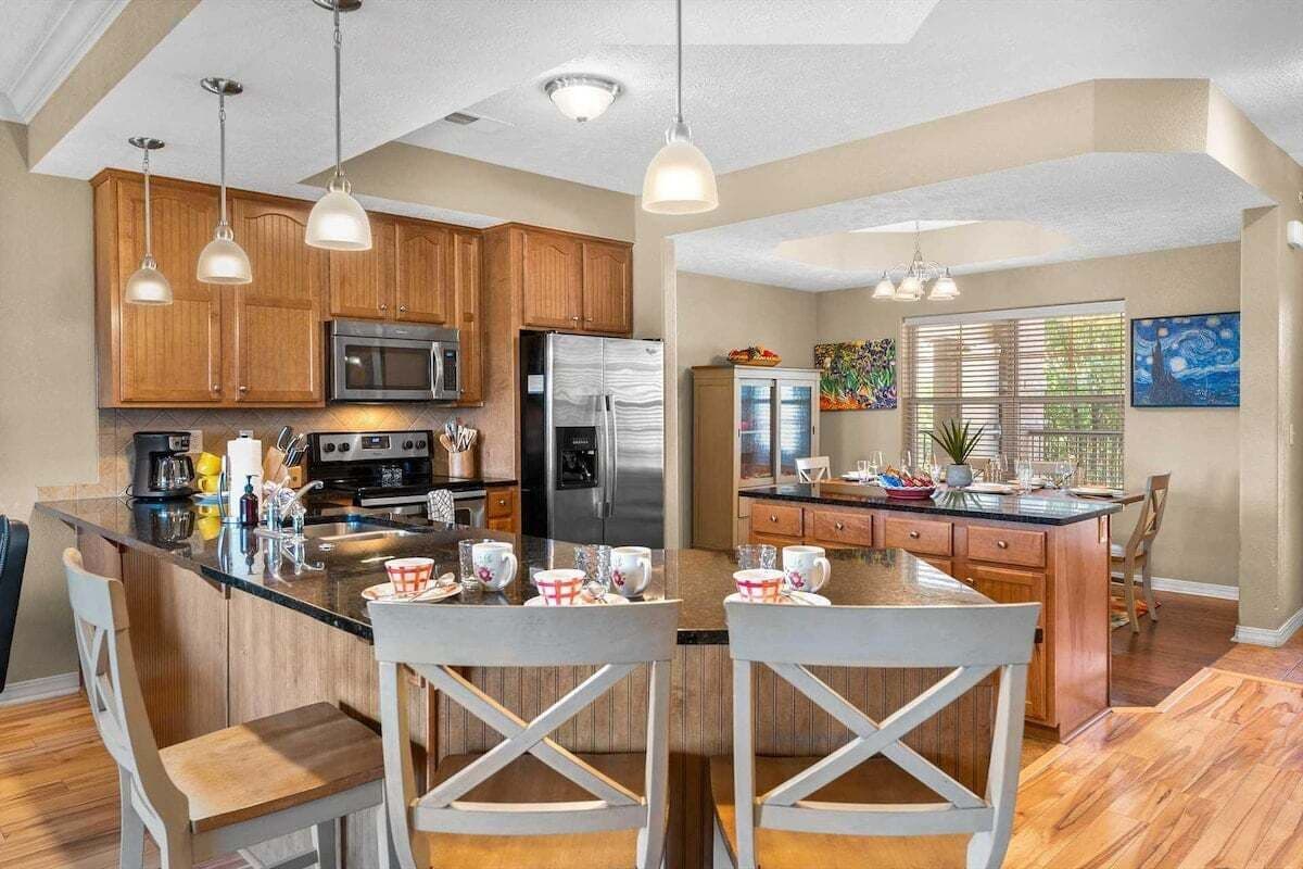 A modern kitchen with wooden cabinets, stainless steel appliances, and pendant lighting.