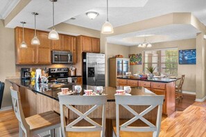 A modern kitchen with wooden cabinets, stainless steel appliances, and pendant lighting. - Luxury Majestic Condo on Table Rock Lake- Free Daily Attraction Tickets (Branson)