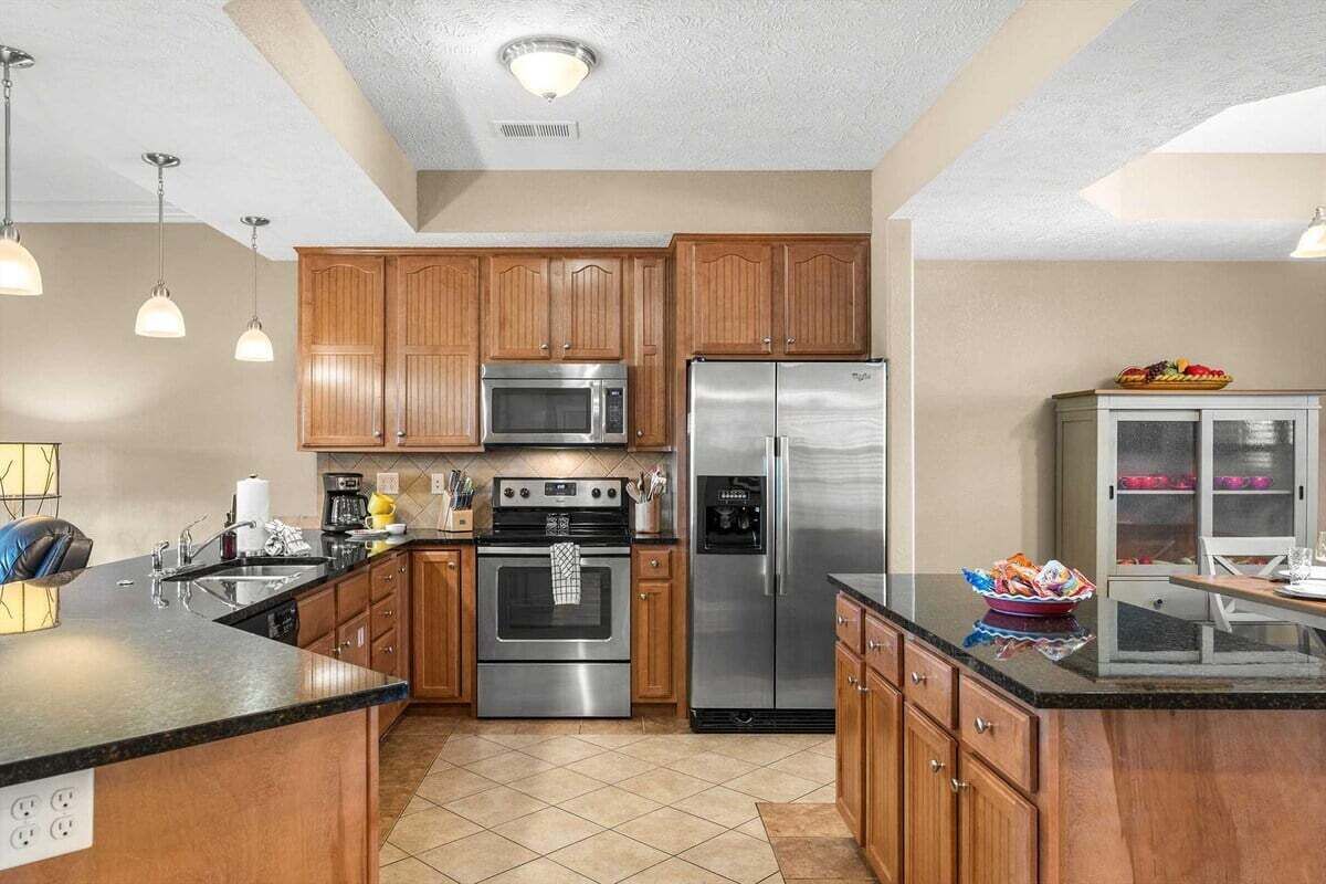 A modern kitchen with wooden cabinets, stainless steel appliances, and a granite countertop.