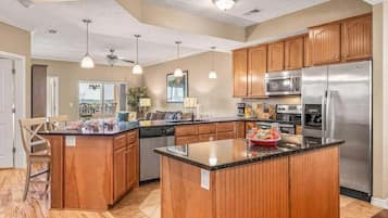 A spacious kitchen with wooden cabinets, stainless steel appliances, and pendant lighting.