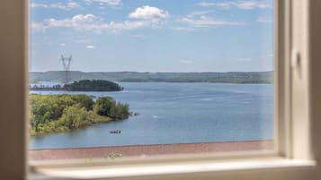 A view of a lake with a power line tower in the distance, a small boat on the water, and a forested island.