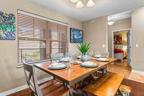 A dining area with a wooden table set for four, a potted plant, and artwork on the walls. - Luxury Majestic Condo on Table Rock Lake- Free Daily Attraction Tickets (Branson)