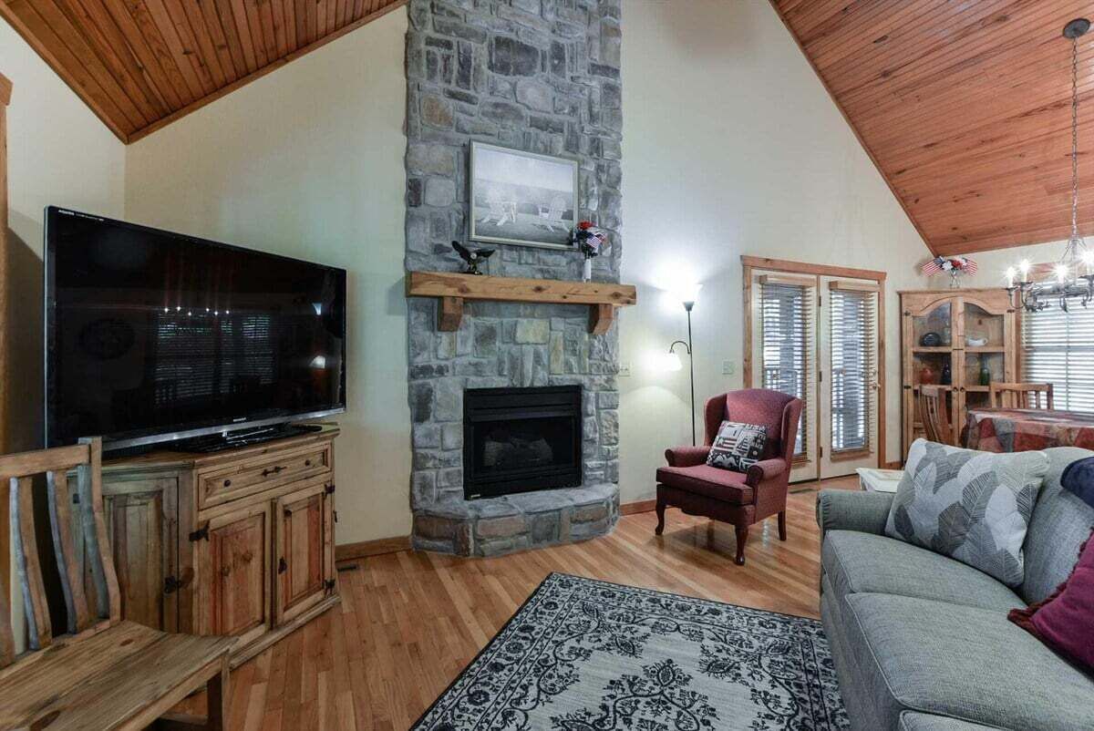 A living room with a stone fireplace, a television, and a red armchair.