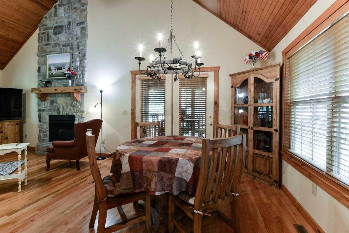 Een eethoek met een stenen open haard, een houten eettafel en stoelen.