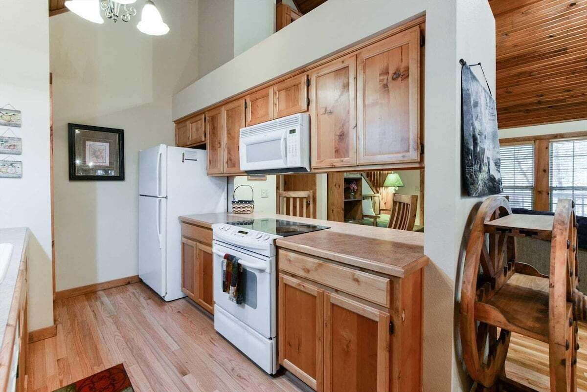 A kitchen with wooden cabinets, a white refrigerator, a microwave, and a stove.
