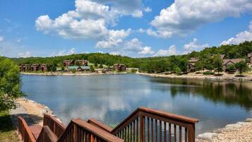 A lakeside property with multiple cabins, a wooden deck, and a clear view of the water.