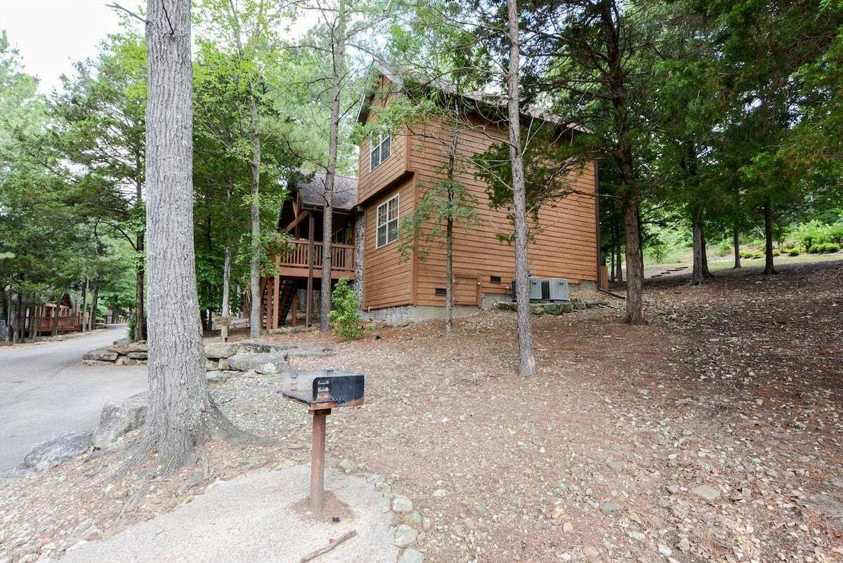 A wooden cabin with a porch, surrounded by trees.