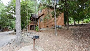 A wooden cabin with a porch, surrounded by trees.