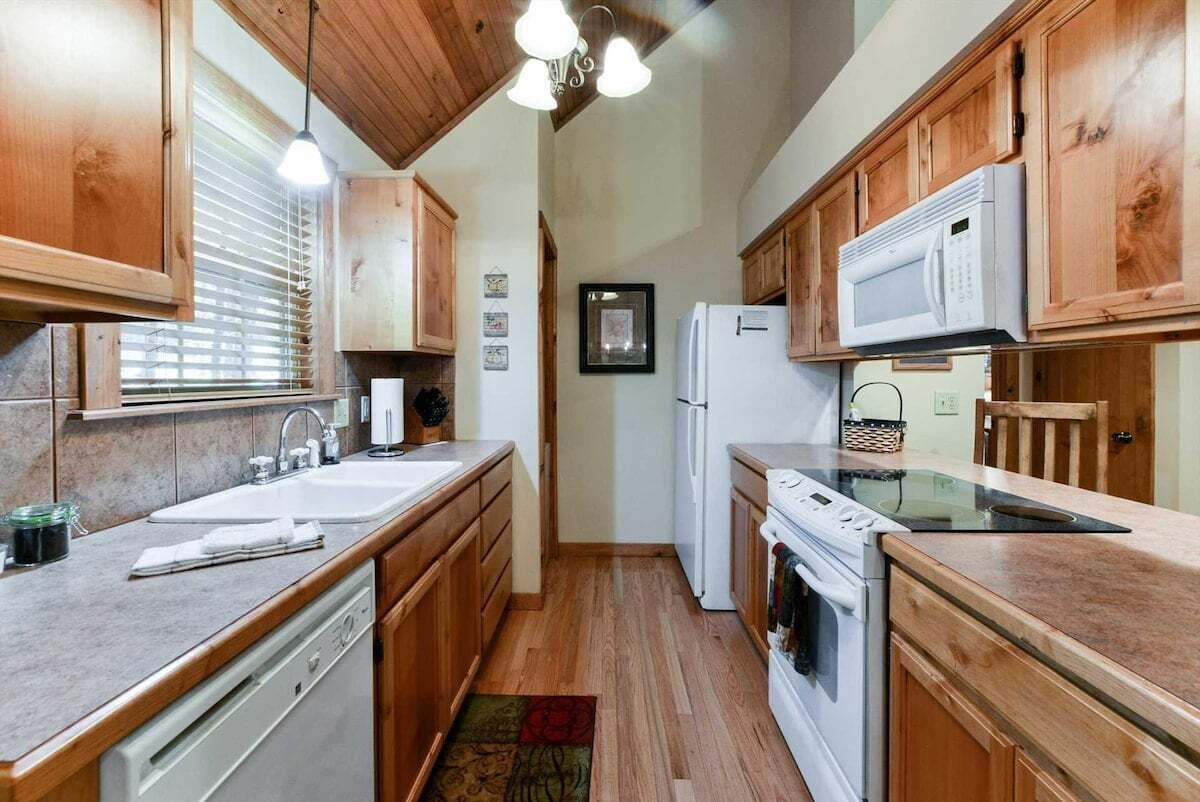 A compact kitchen with wooden cabinets, a microwave, a refrigerator, and a dishwasher.